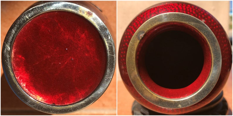 May include: A detailed view of a red and silver vase. The vase has a round shape with a silver rim and a red interior. The exterior is a deep red with a textured pattern. The vase is likely a decorative item.