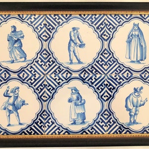 Puede incluir: Obra de arte enmarcada con seis azulejos de cer&aacute;mica azules y blancos, cada uno representando una figura con vestimenta hist&oacute;rica. Los azulejos est&aacute;n colocados sobre un fondo estampado y enmarcados en negro con un borde interior dorado. Una pieza decorativa.