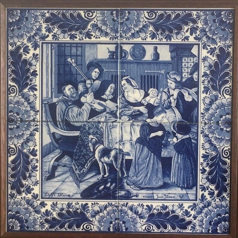 May include: A blue and white Delft tile depicting a scene of people gathered around a table, with a dog in the foreground. The tile is framed in wood and has the text "Delft Blauw" and "naar Jan Steen" at the bottom.