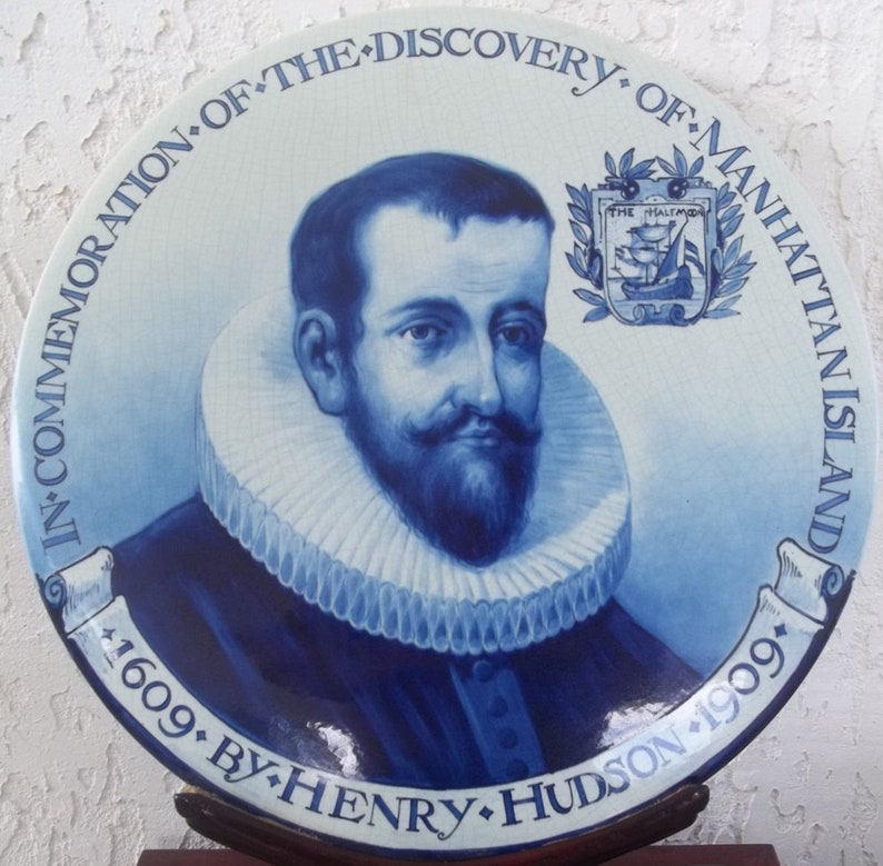 May include: A blue and white ceramic plate commemorating the discovery of Manhattan Island by Henry Hudson. The plate features a portrait of a man with a beard and a ruffled collar, with text that reads "In Commemoration of the Discovery of Manhattan Island 1609 by Henry Hudson 1909."