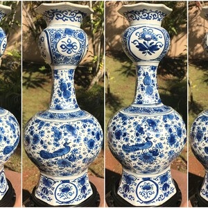 May include: Four blue and white ceramic vases. Each vase has a rounded base, a long neck, and a flared rim. The vases are decorated with floral and peacock patterns. The vases are displayed on a black stand.