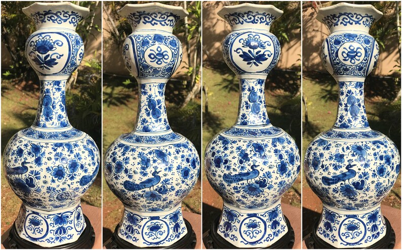 May include: Four blue and white ceramic vases. Each vase has a rounded base, a long neck, and a flared rim. The vases are decorated with floral and peacock patterns. The vases are displayed on a black stand.
