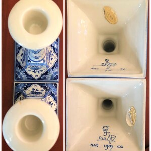 May include: Pair of blue and white Delftware candlestick holders with a gold sticker on the bottom that reads "Delftz 1909." The bottom of the candlestick holders also has the text "N.V.C."