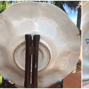 K&ouml;nnte beinhalten: Wei&szlig;e Keramikplatte mit gewelltem Rand und einem blauen und wei&szlig;en Blumenmuster. Die R&uuml;ckseite der Platte tr&auml;gt eine blaue Markierung mit der Aufschrift "D.A.N."