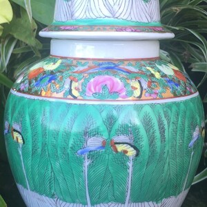 Op de afbeelding: Een witte porseleinen Chinese gemberpot met een groen en gouden bloemenmotief. De deksel heeft een gouden knop en een groen en wit bloemenmotief.