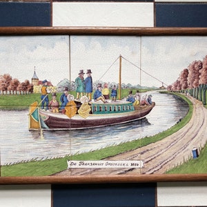 Puede incluir: Un azulejo vintage que representa una escena de canal con un barco lleno de pasajeros. El barco est&aacute; etiquetado como "De Trekschuit Omstreeks 1850". El azulejo est&aacute; enmarcado en madera.