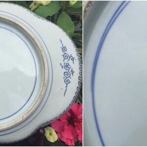 K&ouml;nnte beinhalten: Unterseite eines wei&szlig;-blauen Porzellantellers. Der Teller hat einen gewellten Rand mit blauen dekorativen Mustern. Eine blaue Linie umkreist die Mitte. Der Teller hat einen blauen Stempel mit Text in einer Fremdsprache.