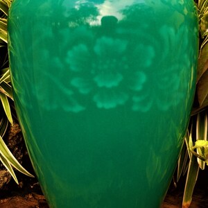 Pu&ograve; includere: Un vaso in ceramica verde con un motivo floreale. Il vaso ha un'ampia apertura e una base stretta. &Egrave; decorato con un motivo floreale bianco.