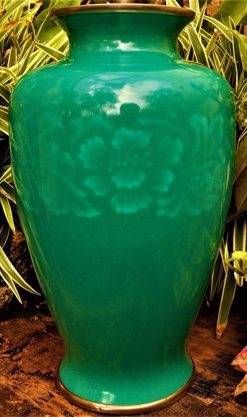 Pu&ograve; includere: Un vaso in ceramica verde con un motivo floreale. Il vaso ha un'ampia apertura e una base stretta. &Egrave; decorato con un motivo floreale bianco.