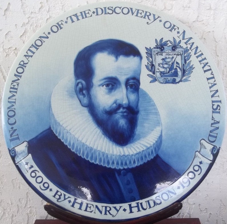 Puede incluir: Un plato de cer&aacute;mica azul y blanco que conmemora el descubrimiento de la isla de Manhattan por Henry Hudson en 1609. El plato presenta un retrato de Hudson y un escudo de armas con un barco.