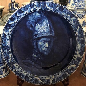 K&ouml;nnte beinhalten: Ein blauer und wei&szlig;er Delft-Teller mit einem Portr&auml;t eines Mannes in einem Helm. Der Teller ist mit einem floralen Rand verziert.