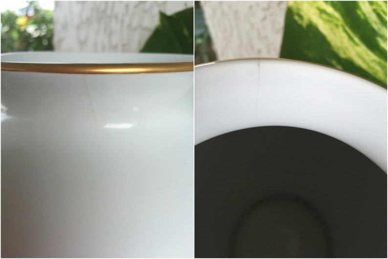 Puede incluir: Primer plano de un jarr&oacute;n de cer&aacute;mica blanco con borde dorado. El jarr&oacute;n tiene un acabado liso y brillante y se puede ver una ligera grieta en el lateral. El interior es oscuro, contrastando con el exterior brillante.