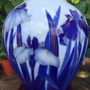 May include: A blue and white porcelain vase with a gold trim and a floral design of blue and white irises.