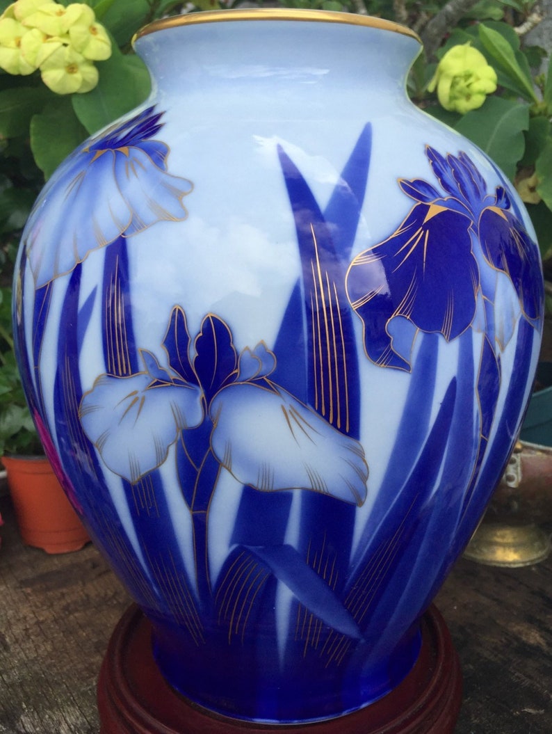 May include: A blue and white porcelain vase with a gold trim and a floral design of blue and white irises.