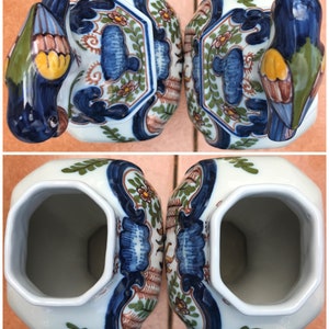 Puede incluir: Par de jarrones vintage de Delftware con dise&ntilde;o de p&aacute;jaro. Los jarrones son blancos con patrones florales azules, verdes y marrones. Los p&aacute;jaros son azules con detalles amarillos y marrones.