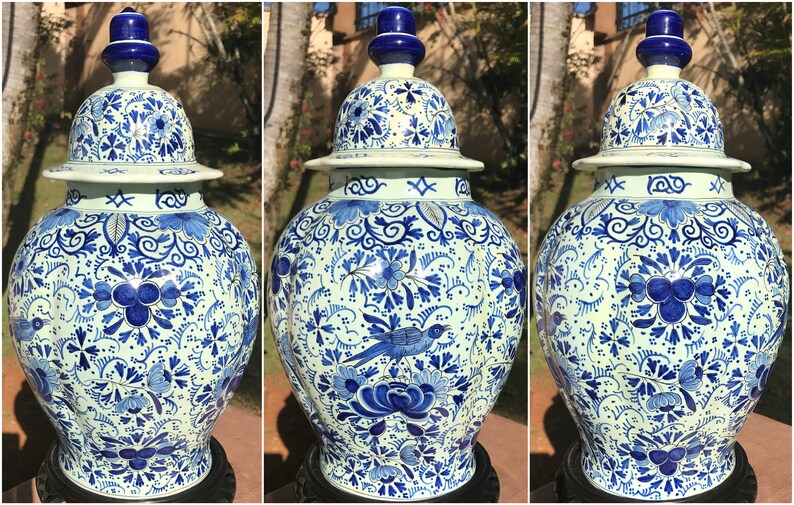 May include: A set of three matching blue and white ceramic ginger jars with lids. The jars feature intricate floral and bird patterns in a classic Delftware style. The jars are displayed on a dark surface.