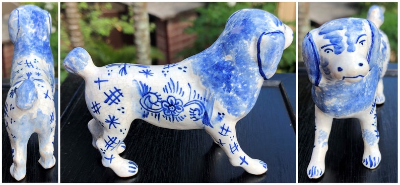 Puede incluir: Figura de perro de cer&aacute;mica en blanco y azul. El perro est&aacute; representado de pie, con orejas azules, espalda y marcas decorativas. Las marcas incluyen patrones florales y geom&eacute;tricos. Un objeto decorativo.