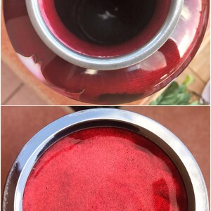 Puede incluir: Un jarr&oacute;n de cer&aacute;mica rojo con un borde plateado. El jarr&oacute;n tiene un acabado brillante y una superficie texturizada. El jarr&oacute;n est&aacute; vac&iacute;o.