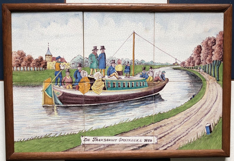 May include: A vintage tile painting depicting a canal scene with a boat full of people. The boat is being pulled by a rope attached to a horse on the towpath. The tile is titled "De Trekschuit Omstreeks 1850".