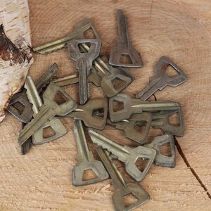 May include: A pile of old, tarnished keys on a wooden surface. The keys are all different shapes and sizes, and some have a worn, aged look.