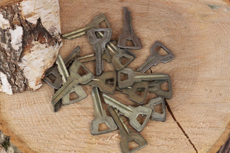 May include: A pile of old, tarnished keys on a wooden surface. The keys are all different shapes and sizes, and some have a worn, aged look.