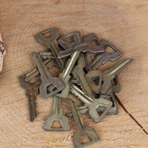 May include: A pile of old, tarnished keys on a wooden surface. The keys are various sizes and shapes, with some having a more ornate design.