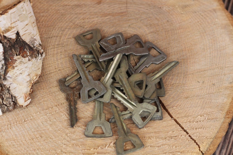 May include: A pile of old, tarnished keys on a wooden surface. The keys are various sizes and shapes, with some having a more ornate design.
