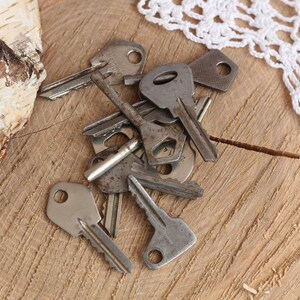 May include: A pile of old, tarnished keys on a wooden surface. The keys are various sizes and shapes, with some having intricate designs.