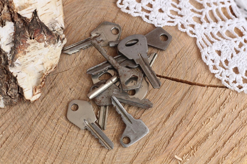 May include: A pile of old, tarnished keys on a wooden surface. The keys are various sizes and shapes, with some having intricate designs.