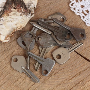 May include: A collection of vintage keys with various designs and finishes, including a key with the number "2114" engraved on it. The keys are arranged on a wooden surface.