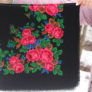 Op de afbeelding: Een zwarte sjaal met een bloemenpatroon in tinten roze, groen, blauw en bruin. De sjaal heeft een gefranst randje.