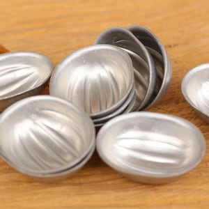 May include: A set of eight silver-colored metal molds for baking. The molds are shaped like half of a walnut shell and have a ribbed texture.