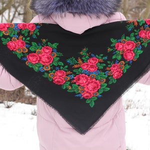 Op de afbeelding: Een zwarte sjaal met een bloemenpatroon in tinten roze, groen en blauw. De sjaal is afgewerkt met een zwarte franje.