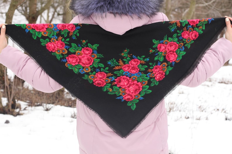 Op de afbeelding: Een zwarte sjaal met een bloemenpatroon in tinten roze, groen en blauw. De sjaal is afgewerkt met een zwarte franje.