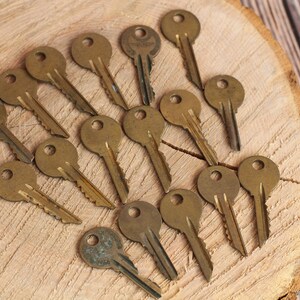 Könnte beinhalten: Eine Sammlung von 17 antiken Messing-Schlüsseln, die fächerförmig auf einer Holzoberfläche angeordnet sind.