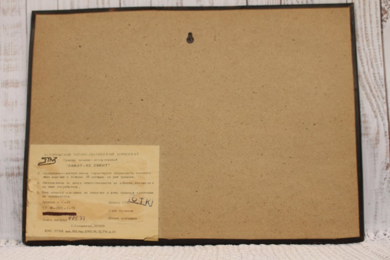 May include: A brown framed picture with a white label on the bottom right corner. The label has text in Russian and includes the words "ЗАКАТ-НЕ ЗАКАТ?" and "ЛОИК!"
