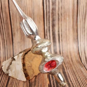 May include: A silver and red glass Christmas tree topper with a star-shaped finial. The topper has a red glass center and a silver glass base.