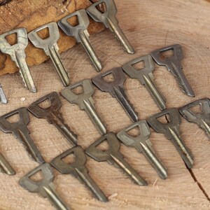 May include: A collection of vintage keys arranged in a fan shape on a wooden surface. The keys are made of metal and have a worn, aged appearance.