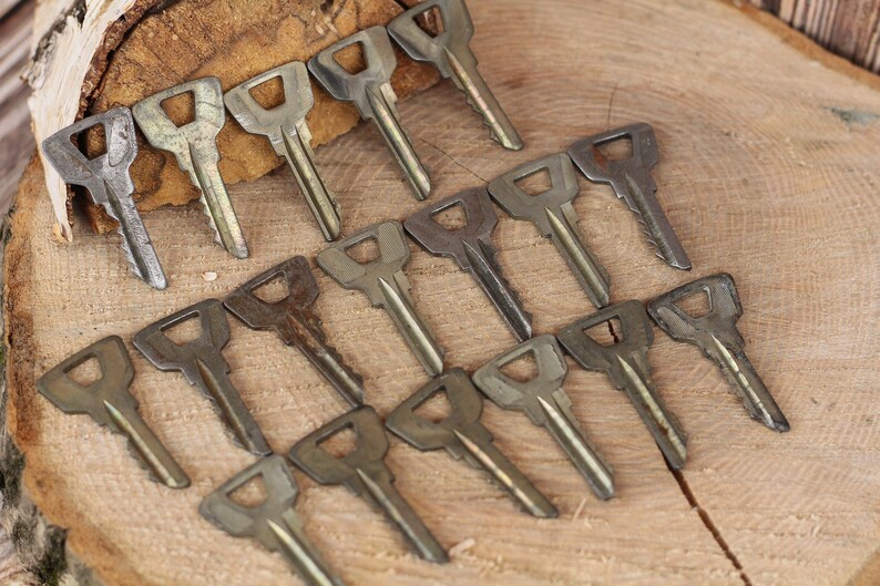 May include: A collection of vintage keys arranged in a fan shape on a wooden surface. The keys are made of metal and have a worn, aged appearance.