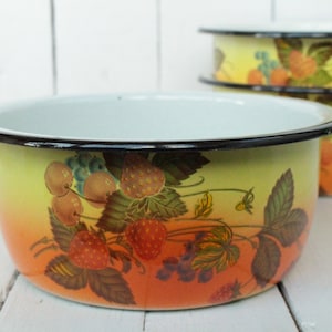 May include: A set of four enamel bowls with a yellow and orange ombre design and a black rim. The bowls feature a floral pattern with strawberries, cherries, and leaves.