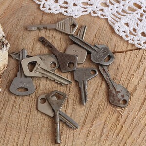 May include: A collection of vintage keys, some with worn metal and others with visible numbers, are scattered on a wooden surface.