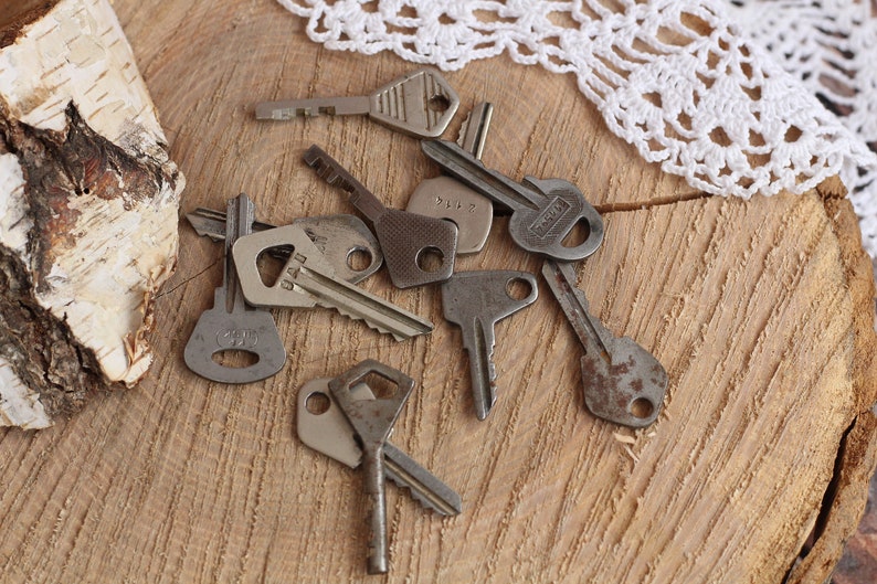 May include: A collection of vintage keys, some with worn metal and others with visible numbers, are scattered on a wooden surface.