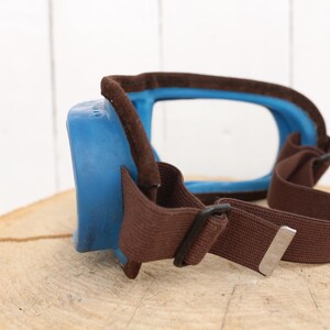 May include: Blue and brown safety goggles with a clear lens and an adjustable strap.