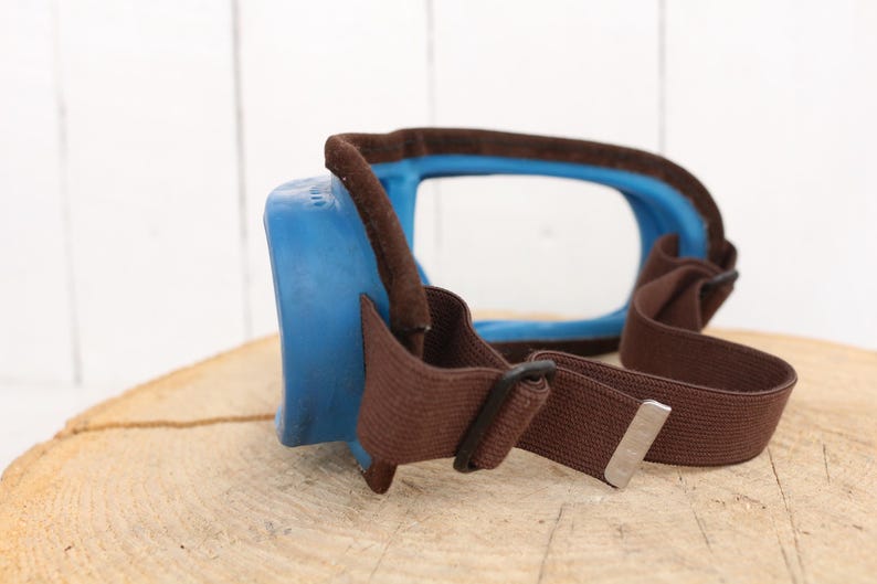 May include: Blue and brown safety goggles with a clear lens and an adjustable strap.
