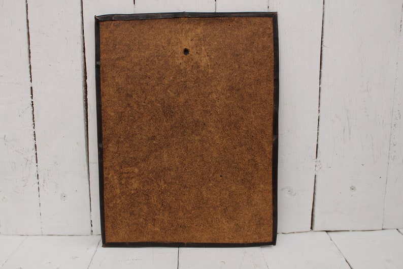 May include: The back of a framed picture with a brown cardboard backing. The frame is black and has a simple design.