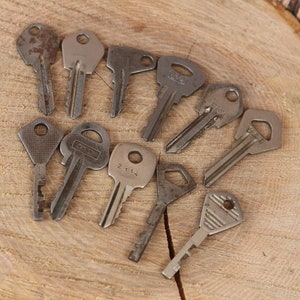 May include: A collection of ten vintage keys, some with visible wear and rust, arranged in a circle on a wooden surface.