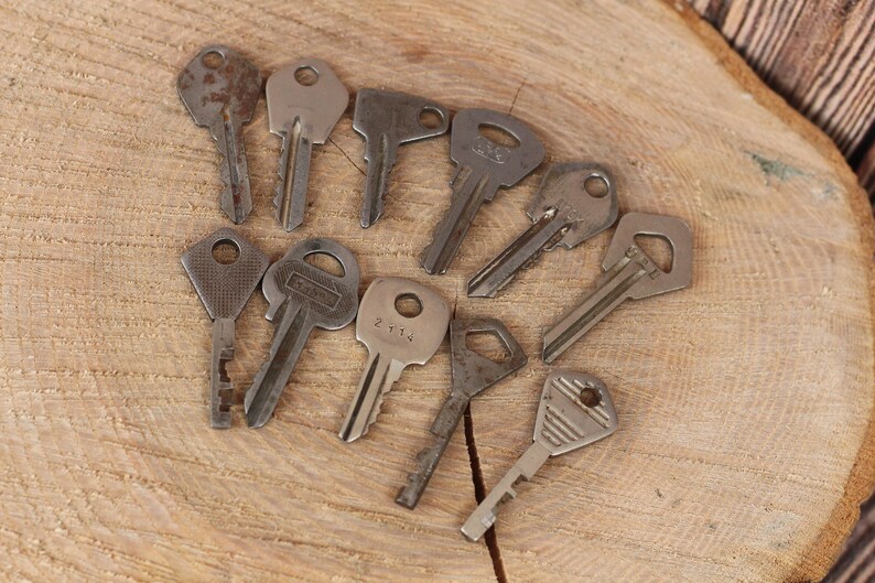 May include: A collection of ten vintage keys, some with visible wear and rust, arranged in a circle on a wooden surface.