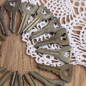 May include: A collection of vintage keys arranged in a circle on a wooden surface with a white crocheted doily.