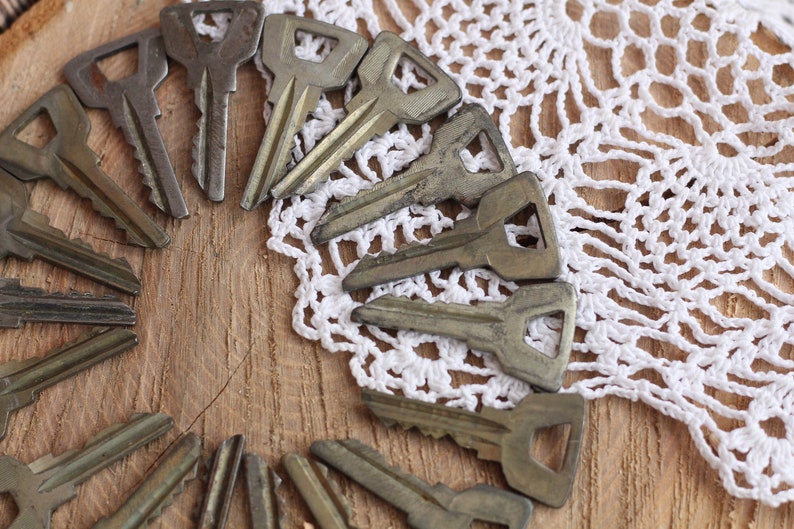 May include: A collection of vintage keys arranged in a circle on a wooden surface with a white crocheted doily.