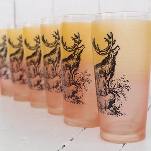 May include: Set of six frosted glass tumblers with a gradient from yellow to pink. Each glass features a black and white illustration of a deer in a forest setting.